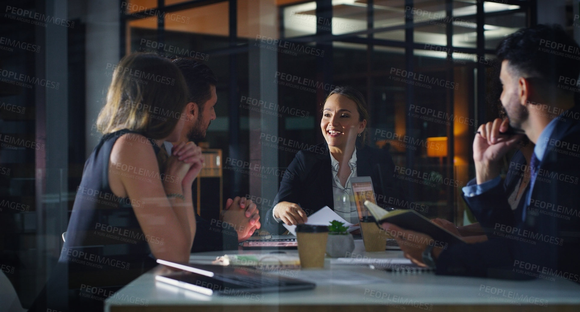 Buy stock photo Cropped shot of a diverse group of businesspeople sitting together and having a meeting in the office late at night