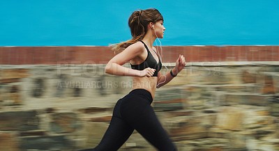 Buy stock photo Cropped shot of an attractive young woman wearing gym wear and running down the street alone