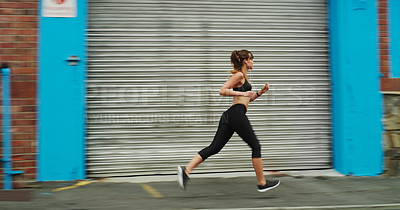 Buy stock photo Full length shot of an attractive young woman wearing gym wear and running down the street alone