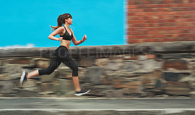 Buy stock photo Full length shot of an attractive young woman wearing gym wear and running down the street alone