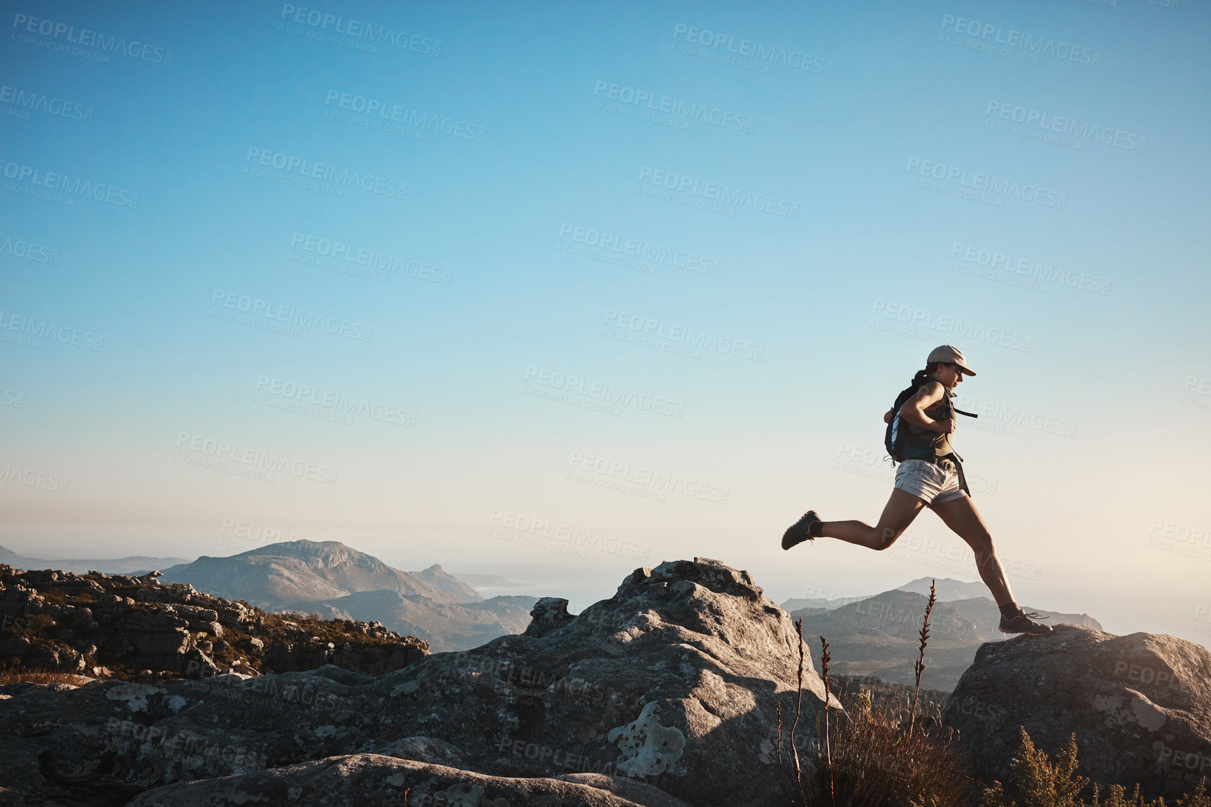 Buy stock photo Hiking, woman and jump on rocks for fitness, wellness and energy at sky mockup. Trekking, female athlete and confident on mountain with gap, travel or adventure in nature space for exercise or growth