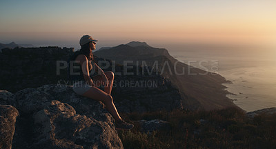 Buy stock photo Shot of a young woman hiking up a mountain at sunset
