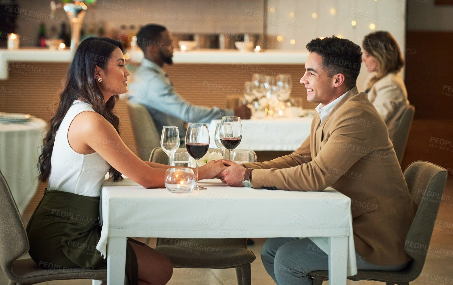 Buy stock photo Couple in restaurant for dinner, holding hands and romantic date on Valentines day, love and celebrate holiday. Commitment, interracial relationship and man with woman, trust, support and celebration