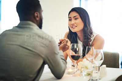 Buy stock photo Couple, holding hands and wine in restaurant with talking, love and romance for valentines day date in night. Black man, asian woman and conversation for bonding, luxury fine dining and celebration