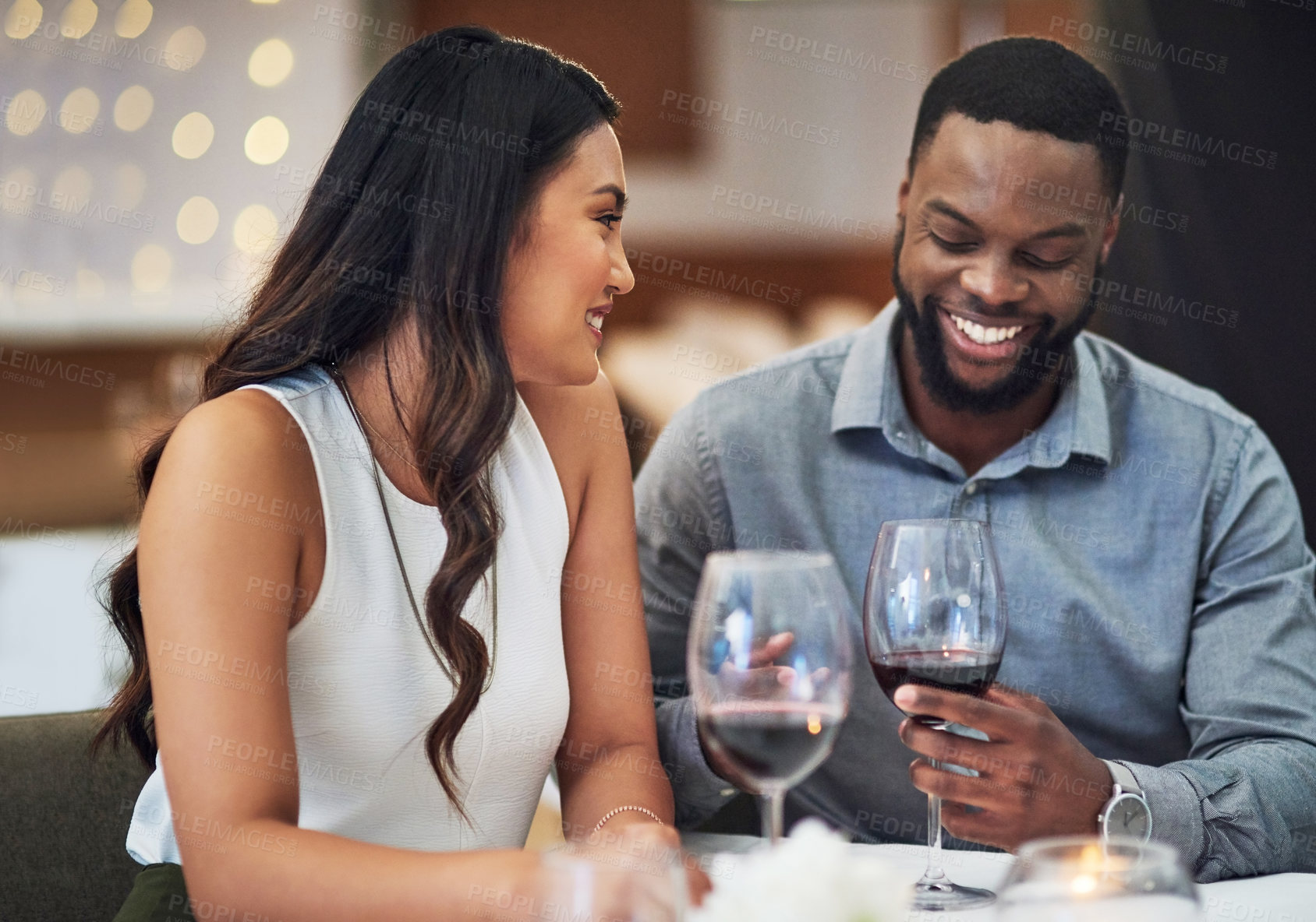 Buy stock photo Cropped shot of an affectionate young couple enjoying a date together in a restaurant
