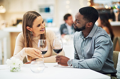 Buy stock photo Love, wine and interracial couple on date for fine dining, restaurant or valentines celebration together. Black man and happy woman with romance alcohol glasses, celebrate and luxury in night bokeh