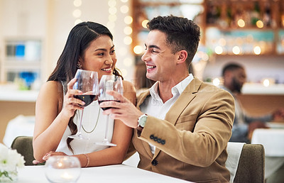 Buy stock photo Cropped shot of an affectionate  young couple making a celebratory toast while sitting in a restaurant