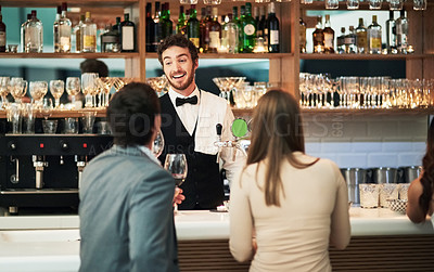 Buy stock photo Cropped shot of a handsome young barman serving a young couple in a bar