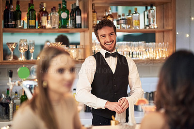 Buy stock photo Cropped shot of a handsome young waiter smiling while standing in a bar