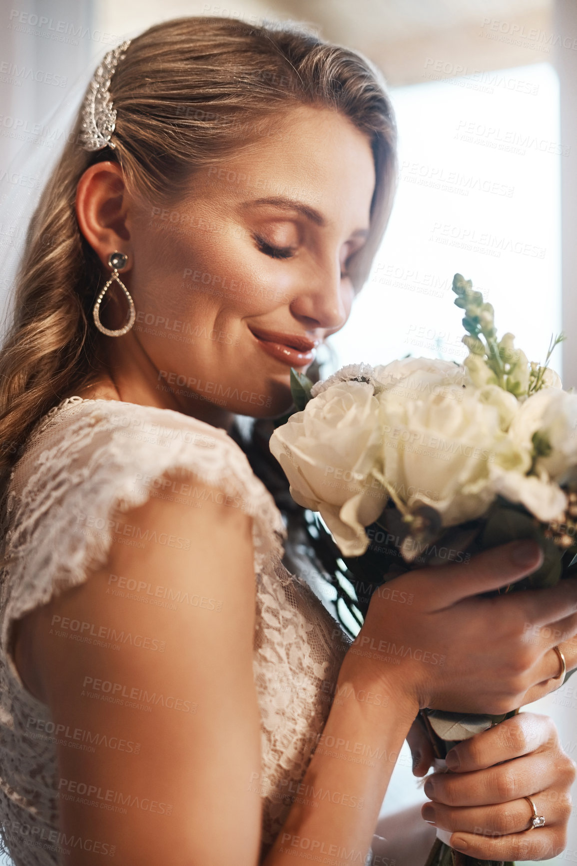 Buy stock photo Cropped shot of an attractive young bride standing in the dressing room alone and smelling her bouquet of flowers