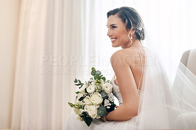 Buy stock photo Cropped shot of an attractive young bride sitting alone in the dressing room and holding her bouquet of flowers