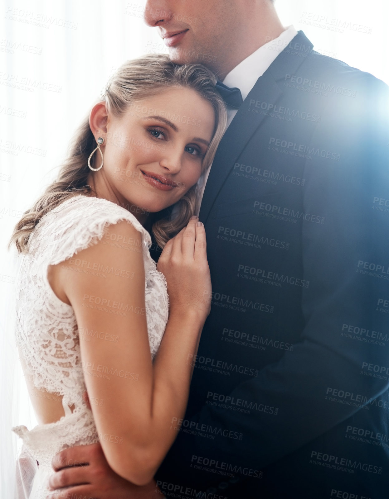 Buy stock photo Cropped portrait of an attractive young bride standing indoors and hugging her newlywed husband