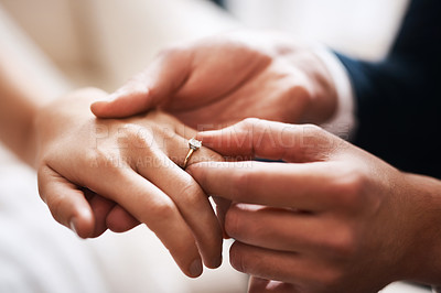 Buy stock photo Cropped shot of an unrecognizable groom putting a diamond ring on his wife's finger during their wedding