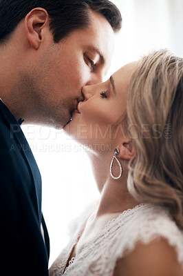 Buy stock photo Cropped shot of an affectionate young couple standing indoors together and kissing after their wedding