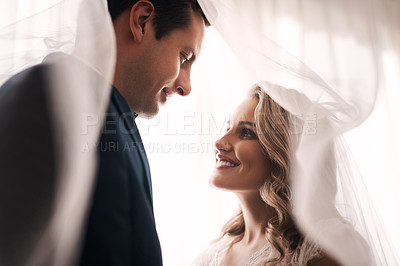 Buy stock photo Cropped shot of a happy young couple standing indoors and looking lovingly at each other after their wedding