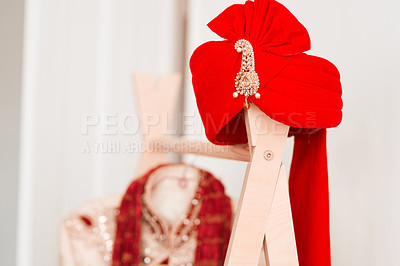 Buy stock photo Shot of a turban and men’s clothing hanging on a rack in a bedroom before a traditional Indian wedding ceremony
