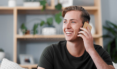 Buy stock photo Cropped shot of a handsome young man sitting alone in his living room at home and using his cellphone