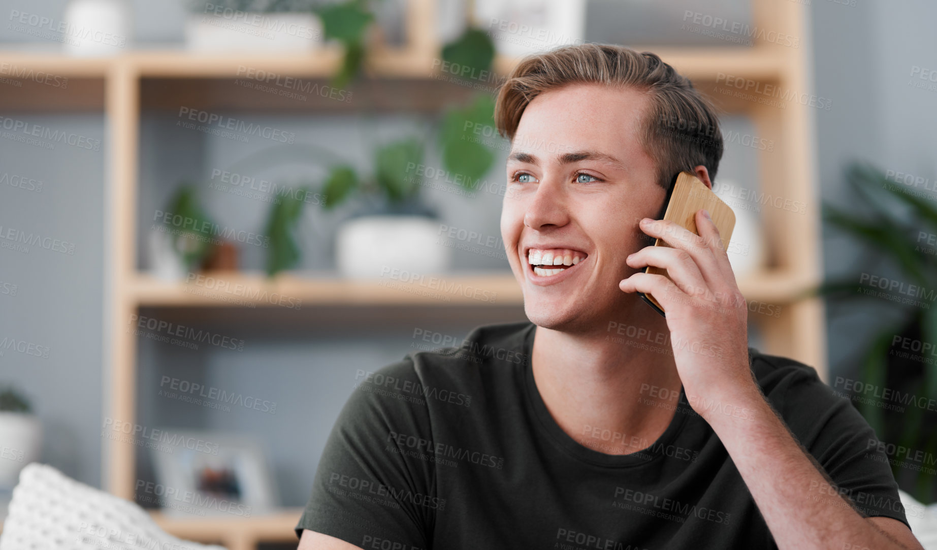 Buy stock photo Cropped shot of a handsome young man sitting alone in his living room at home and using his cellphone