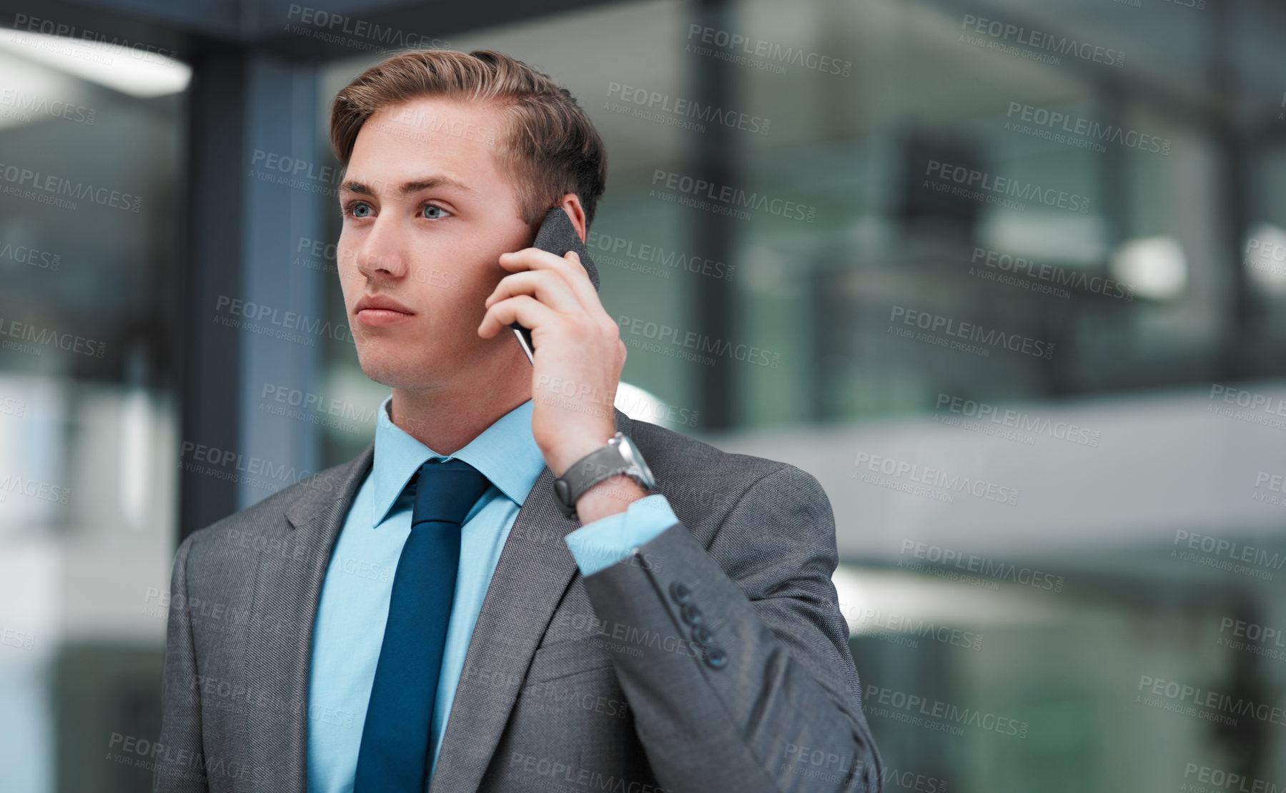 Buy stock photo Cropped shot of a handsome young businessman standing alone in his office and using his cellphone