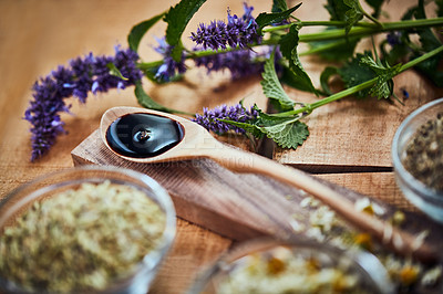 Buy stock photo Shot of a wooden spoon with dark liquid in it surrounded by fresh lavender on a table