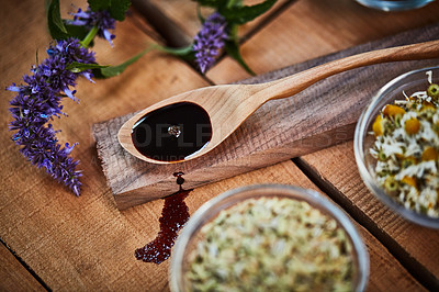 Buy stock photo Shot of a wooden spoon with dark liquid in it surrounded by fresh lavender on a table