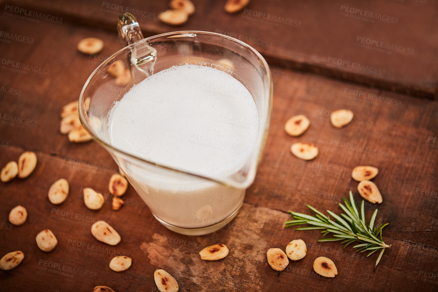 Buy stock photo Shot of a jug of milk surrounded by nuts on a table