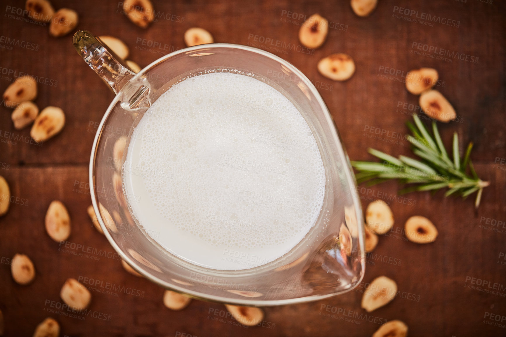 Buy stock photo Shot of a jug of milk surrounded by nuts on a table