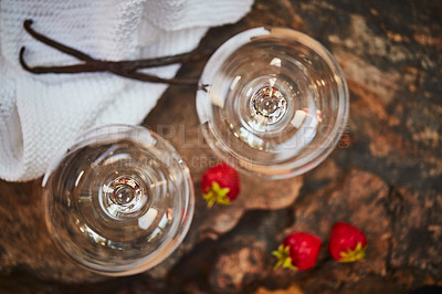 Buy stock photo Shot of a two empty glasses on a table with strawberries next to them