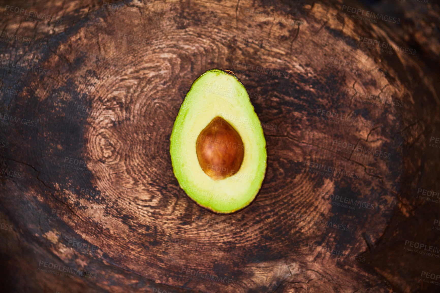 Buy stock photo High angle shot of an avocado cut in half on a wooden table