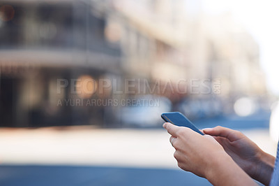 Buy stock photo Cropped shot of an unrecognizable young woman sending text messages while out in the city