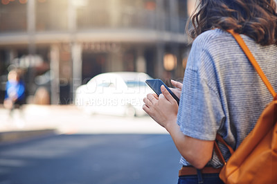 Buy stock photo Rearview shot of an unrecognizable young woman sending text messages while out in the city
