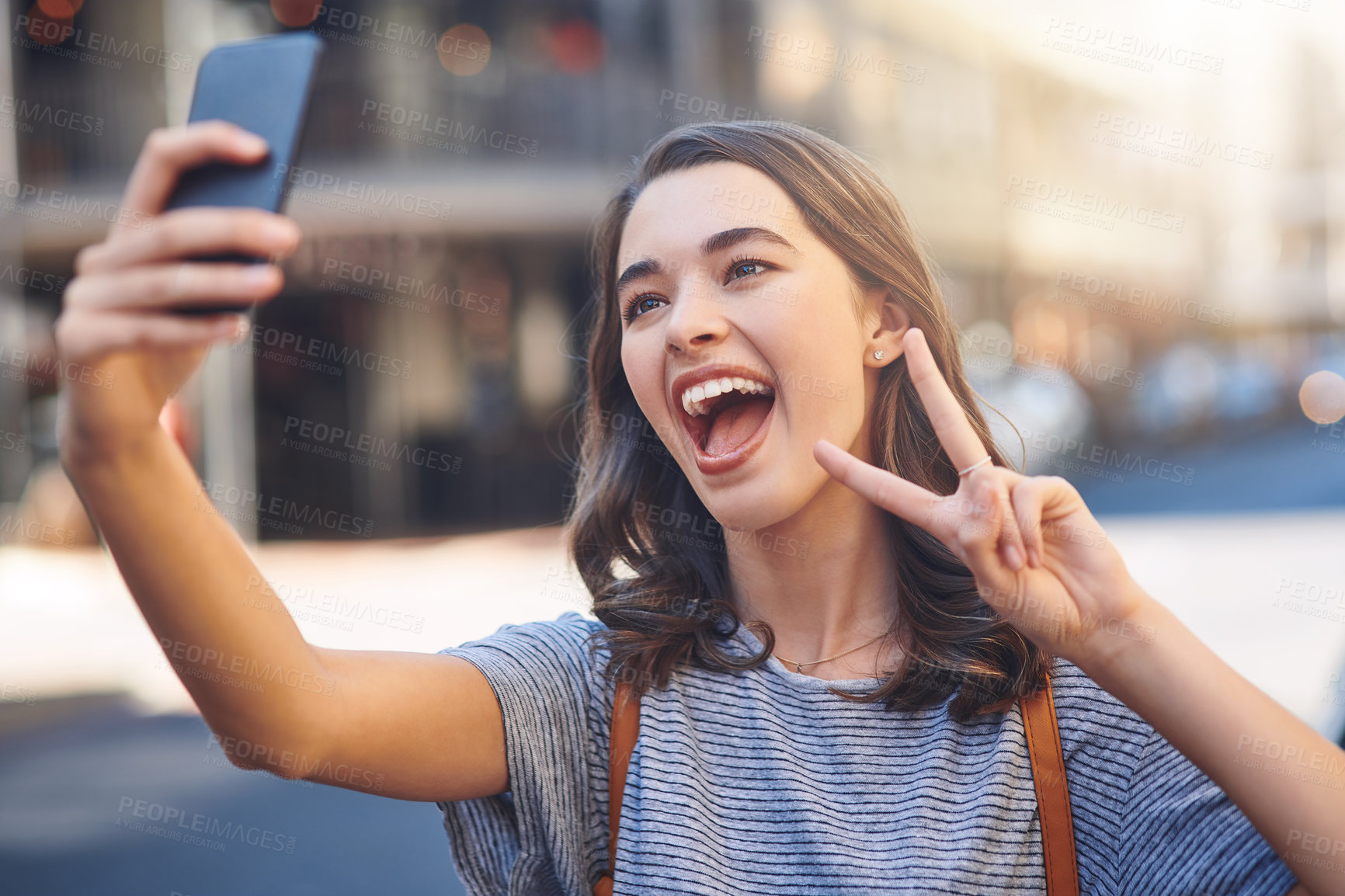 Buy stock photo Cropped shot of an attractive young woman taking selfies while spending her day out in the city