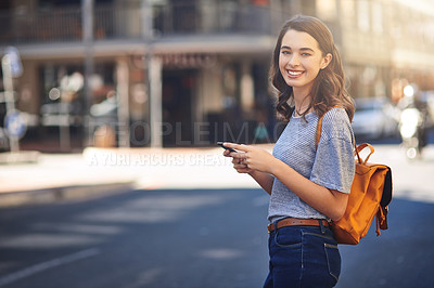 Buy stock photo Cropped portrait of an attractive young woman sending text messages while spending her day out in the city