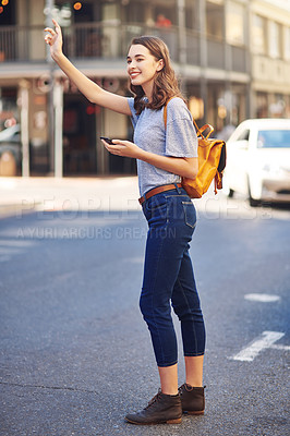Buy stock photo Full length shot of an attractive young woman sending a text message while hailing a taxi out in the city