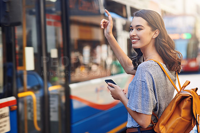 Buy stock photo Cropped shot of an attractive young woman sending a text message while hailing a taxi out in the city