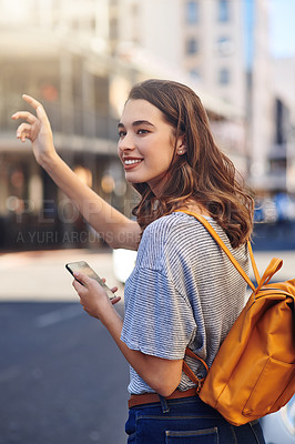 Buy stock photo Cropped shot of an attractive young woman sending a text message while hailing a taxi out in the city