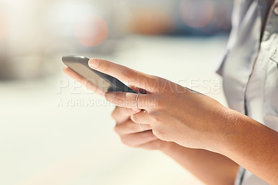 Buy stock photo Cropped shot of an unrecognizable young woman sending text messages while out in the city
