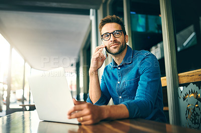 Buy stock photo Cropped shot of a handsome young businessman sitting alone and looking contemplative while using his cellphone in a cafe