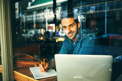 Buy stock photo Cropped portrait of a handsome young businessman sitting in a cafe alone and writing in a notebook