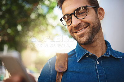 Buy stock photo Shot of a handsome man using his cellphone while out in the city