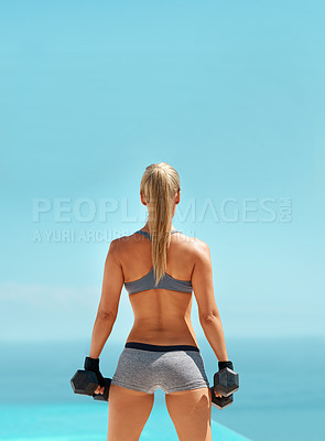 Buy stock photo Rearview shot of an unrecognizable young woman exercising with dumbbells outdoors