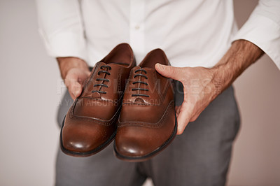 Buy stock photo Cropped shot of an unrecognizable bridegroom holding the shoes he's going to wear in a dressing room