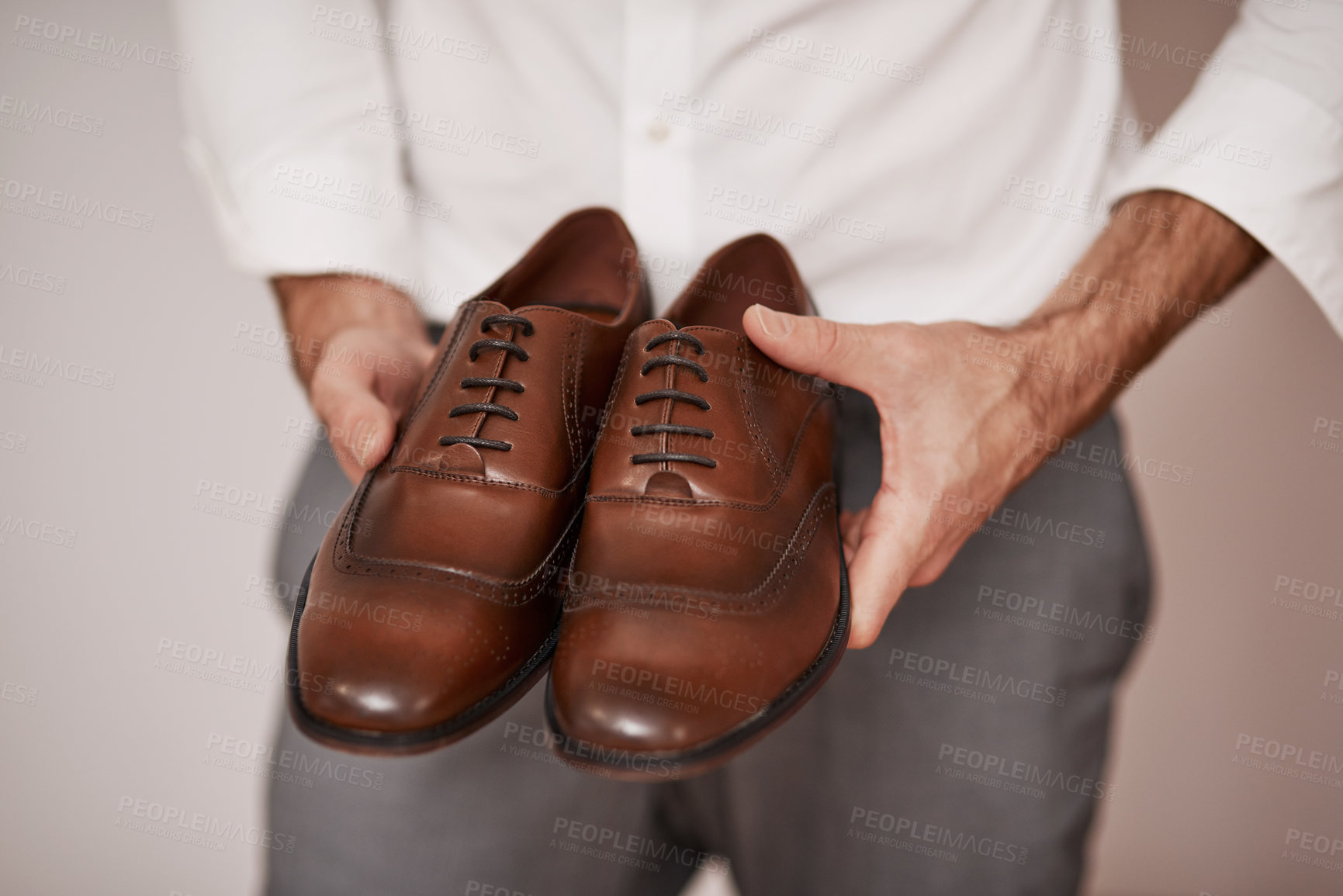 Buy stock photo Leather shoes, hands and businessman in studio for dressing, preparing and professional for work. Man, arms and holding footwear on gray background for stylish, fashion and new position in job