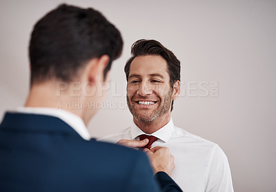 Buy stock photo Cropped shot of a young best man adjusting the groom's tie in a dressing room on the wedding day
