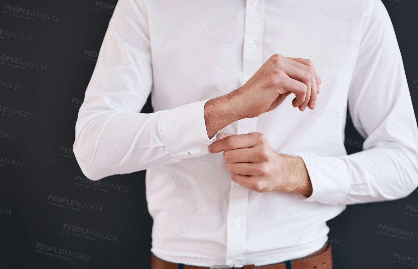 Buy stock photo Cropped shot of an unrecognizable bridegroom adjusting his shirt's button in preparation for his wedding