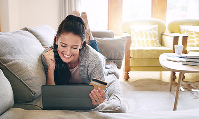 Buy stock photo Full length shot of an attractive young woman cheering while holding a digital tablet and a credit card on her couch at home