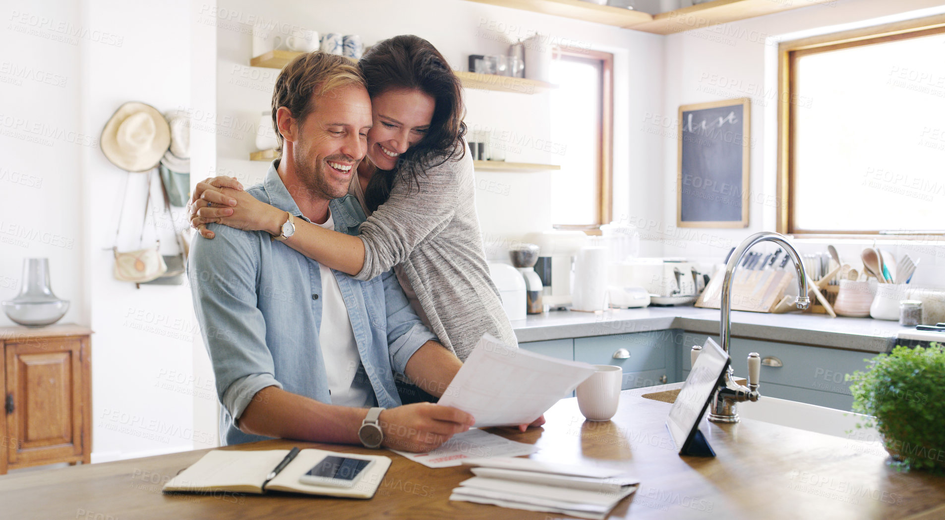 Buy stock photo Cropped shot of an affectionate young woman embracing her husband cheerfully while going through their budget at home