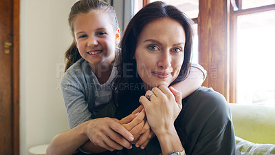 Buy stock photo Cropped portrait of an affectionate young girl embracing her mother in their living room at home