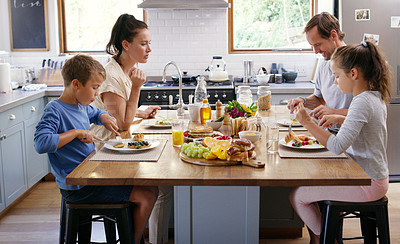 Buy stock photo Cropped shot of two affectionate young parents having breakfast with their kids in the kitchen at home