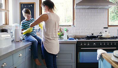 Buy stock photo Cropped shot of an affectionate young mother helping her son to put on rubber gloves while preparing to clean their kitchen